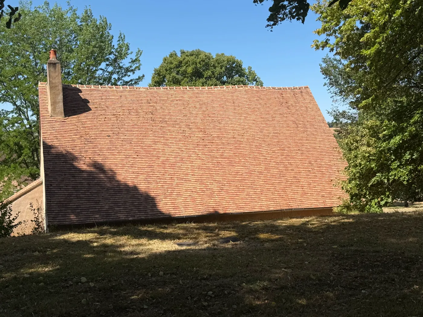 La toiture en tuile plate de la grange après traitement : la tuile a retrouvé sa teinte terre cuite uniforme, sans mousse.